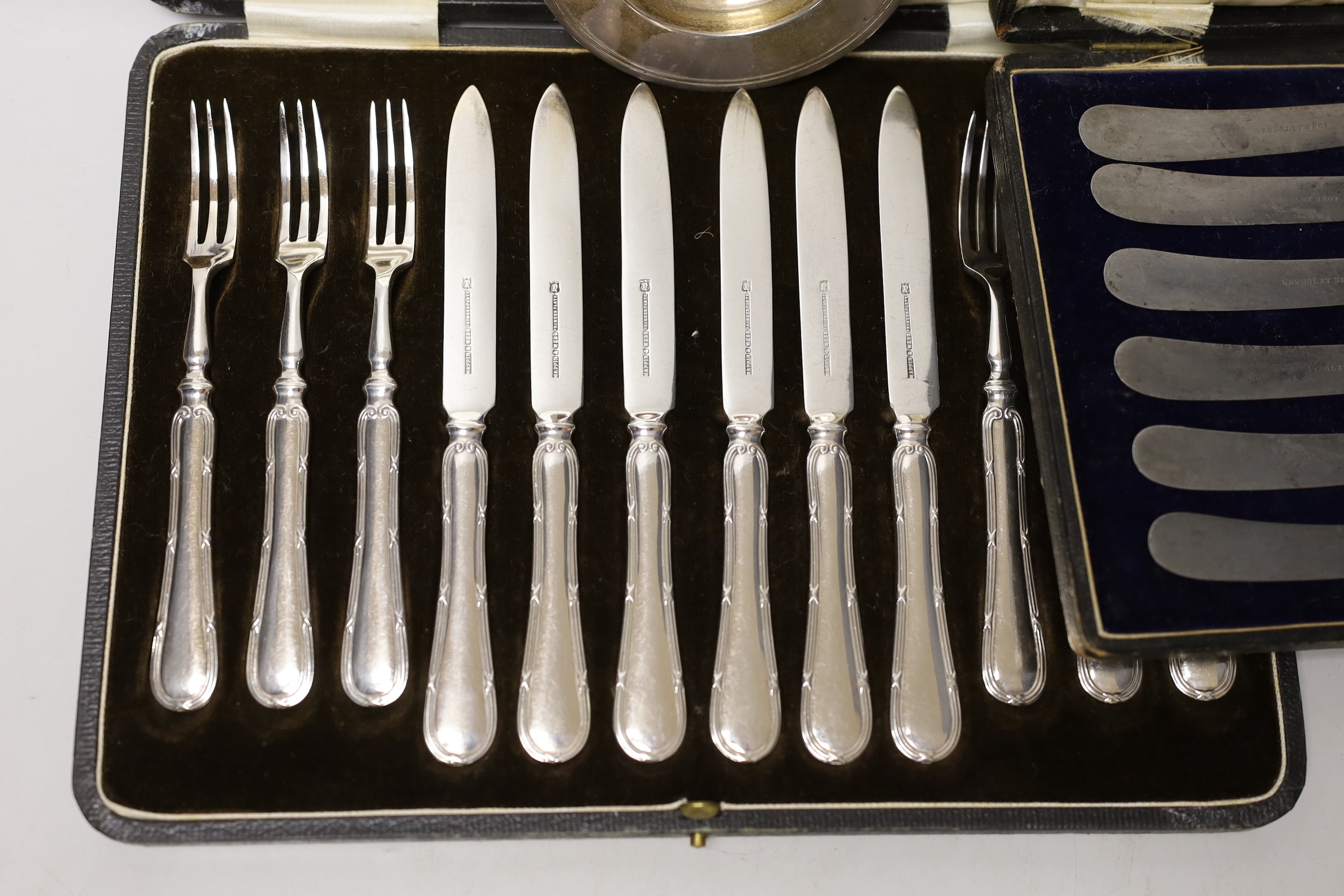 A cased set of six silver coffee spoons, a cased set of six silver-handled dessert knives, a small silver dish and a cased set of plated dessert knives and forks